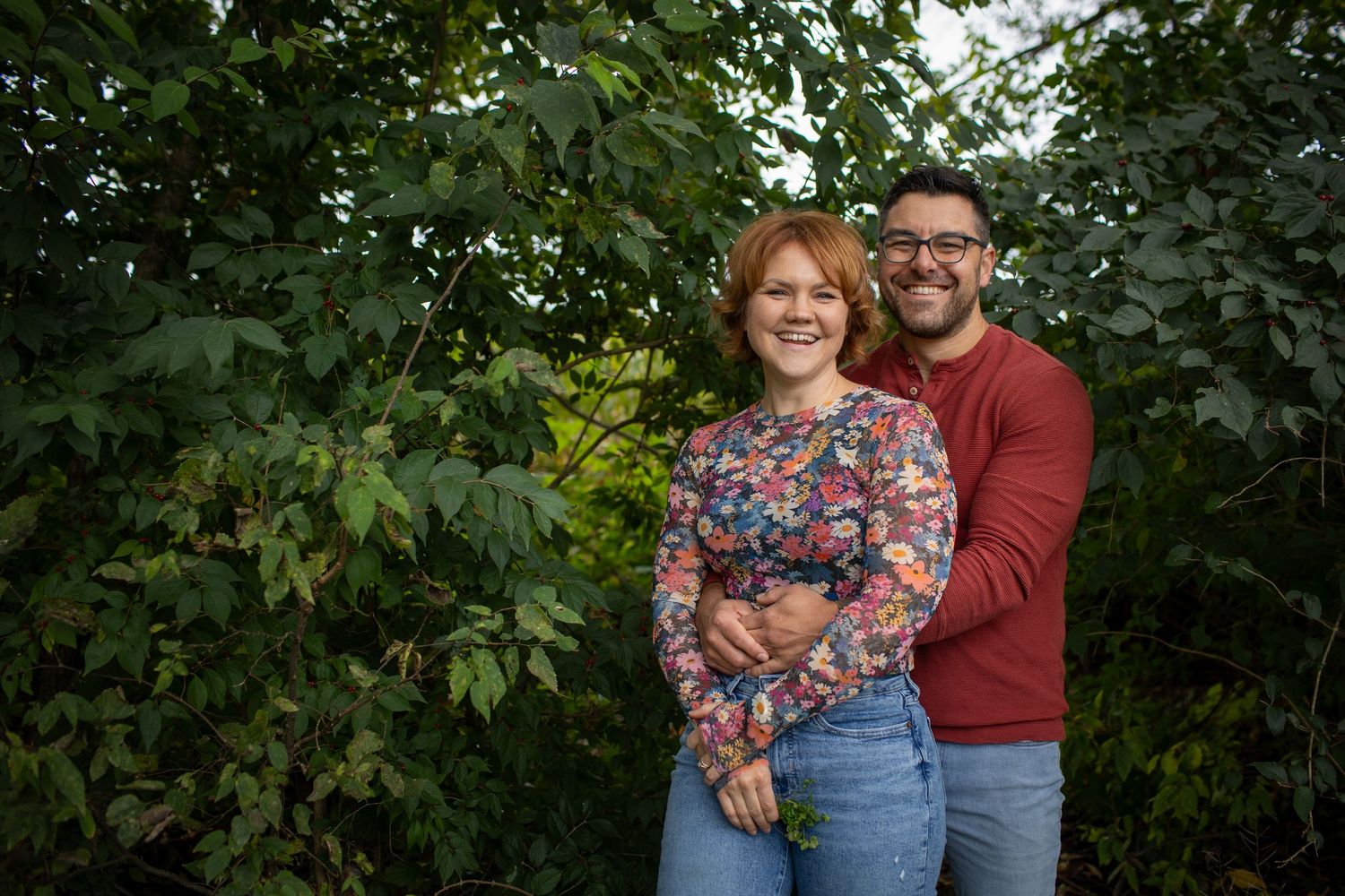 Couple enjoying a romantic moment together in a lush green garden setting.