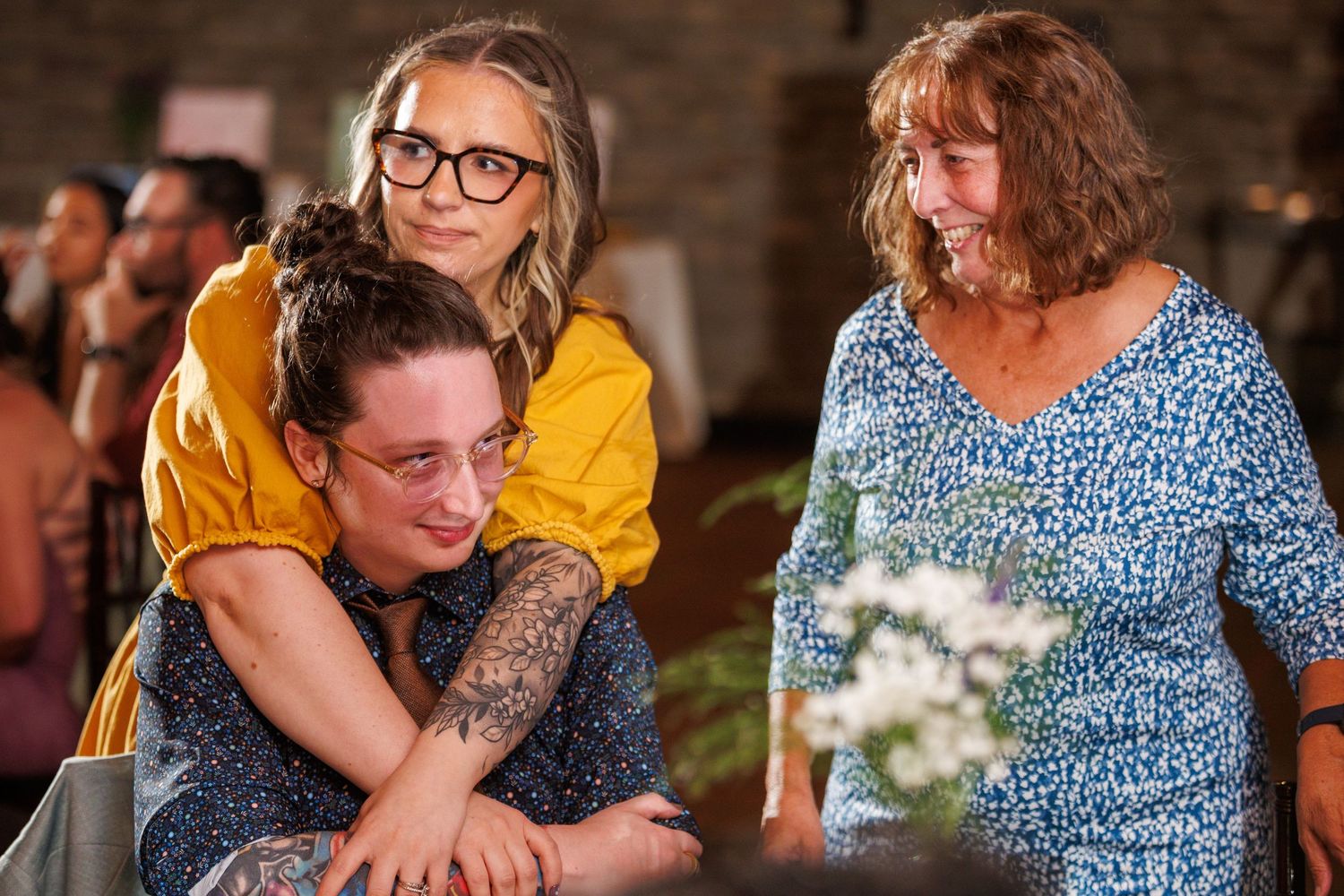 Three women share a warm embrace at a wedding celebration.