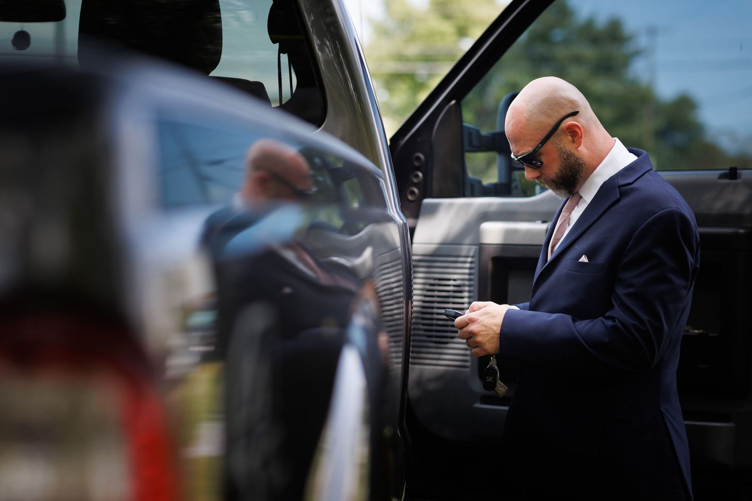 A person in formal attire enters a black luxury vehicle while being photographed by onlookers.
