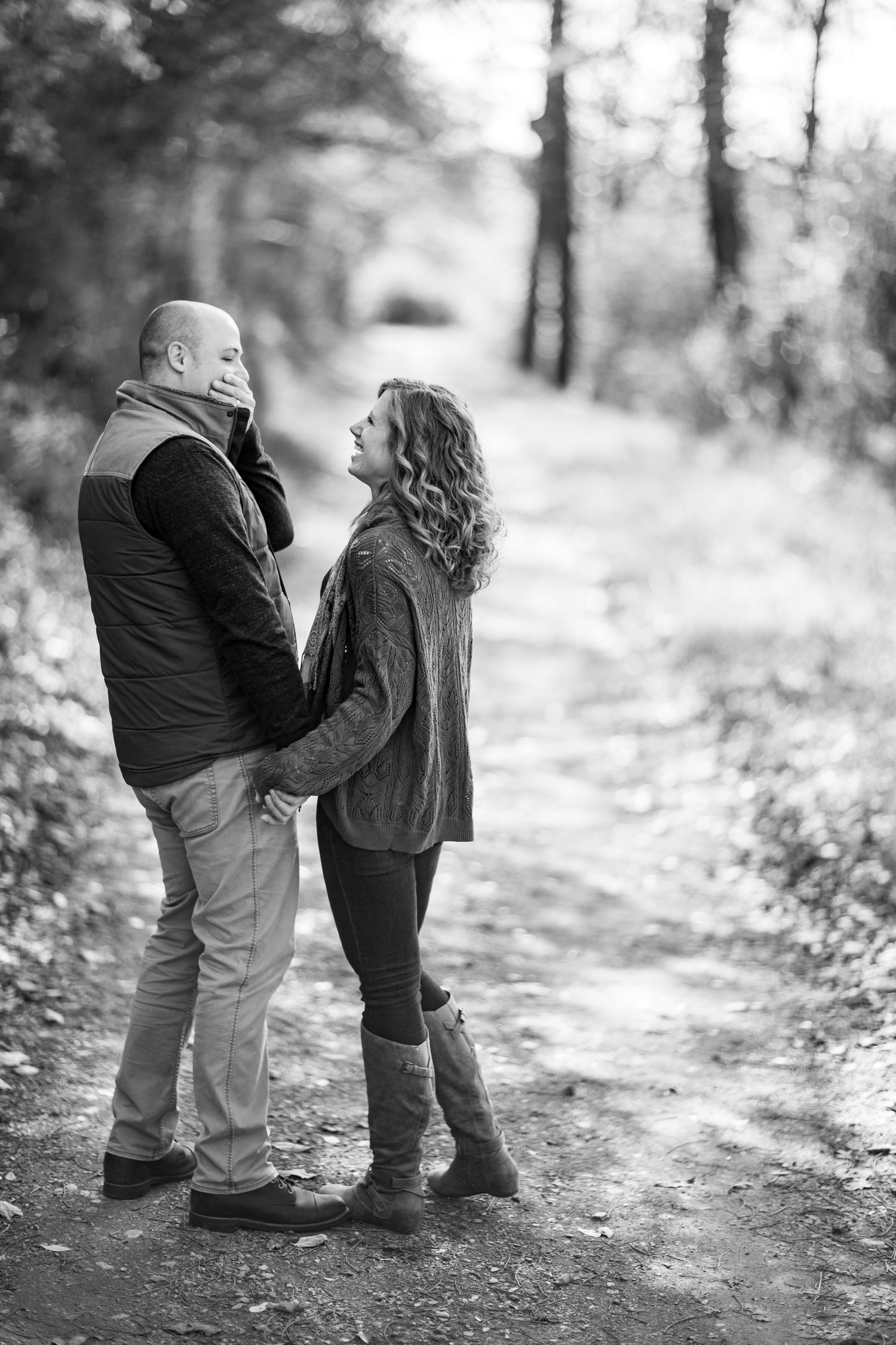 A series of black and white photos showing two young children playing and hugging on a wooded path.