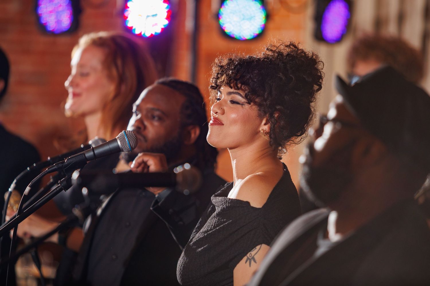 Diverse live wedding band performs soulfully on stage with colorful neon lights in the background.