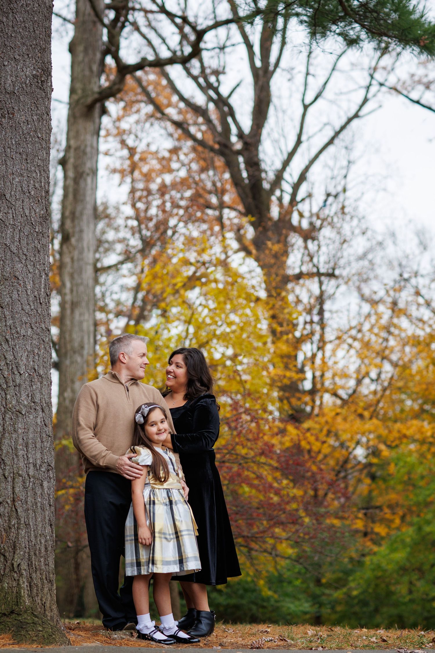 A family poses together on a wooded path surrounded by vibrant fall foliage and autumn colors.