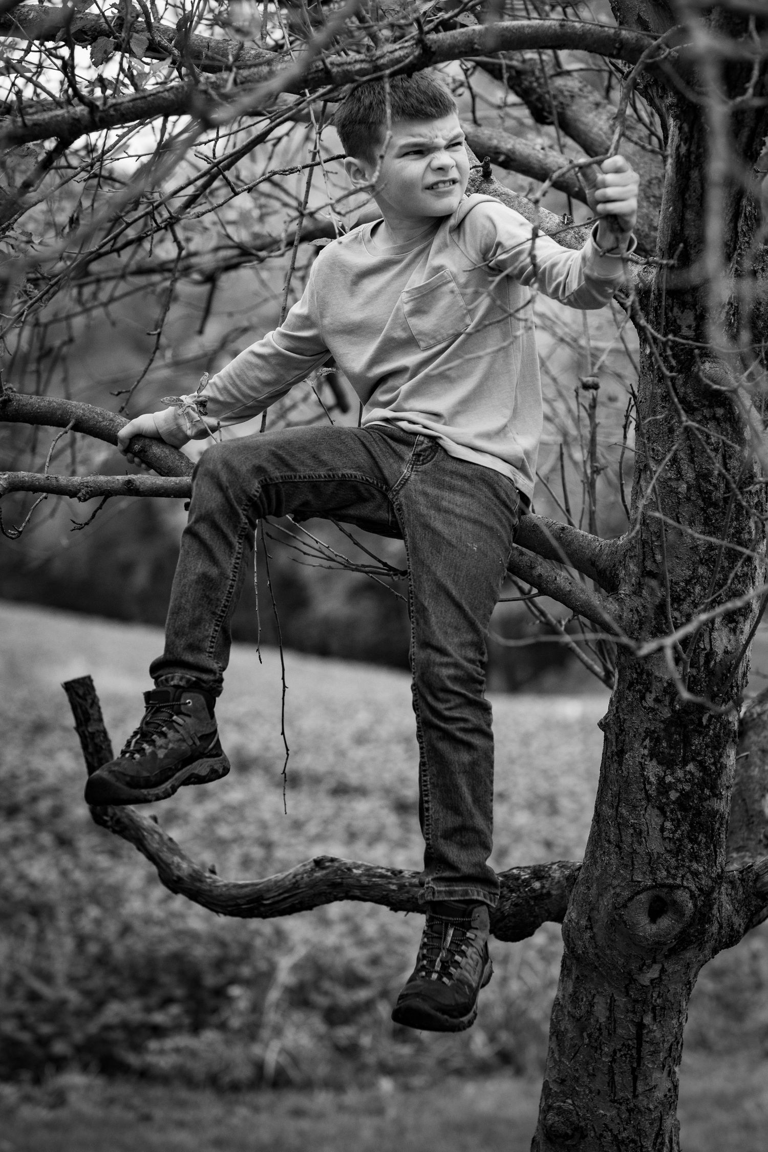 Black and white sequence showing boots climbing up a gnarled tree branch in an outdoor setting.