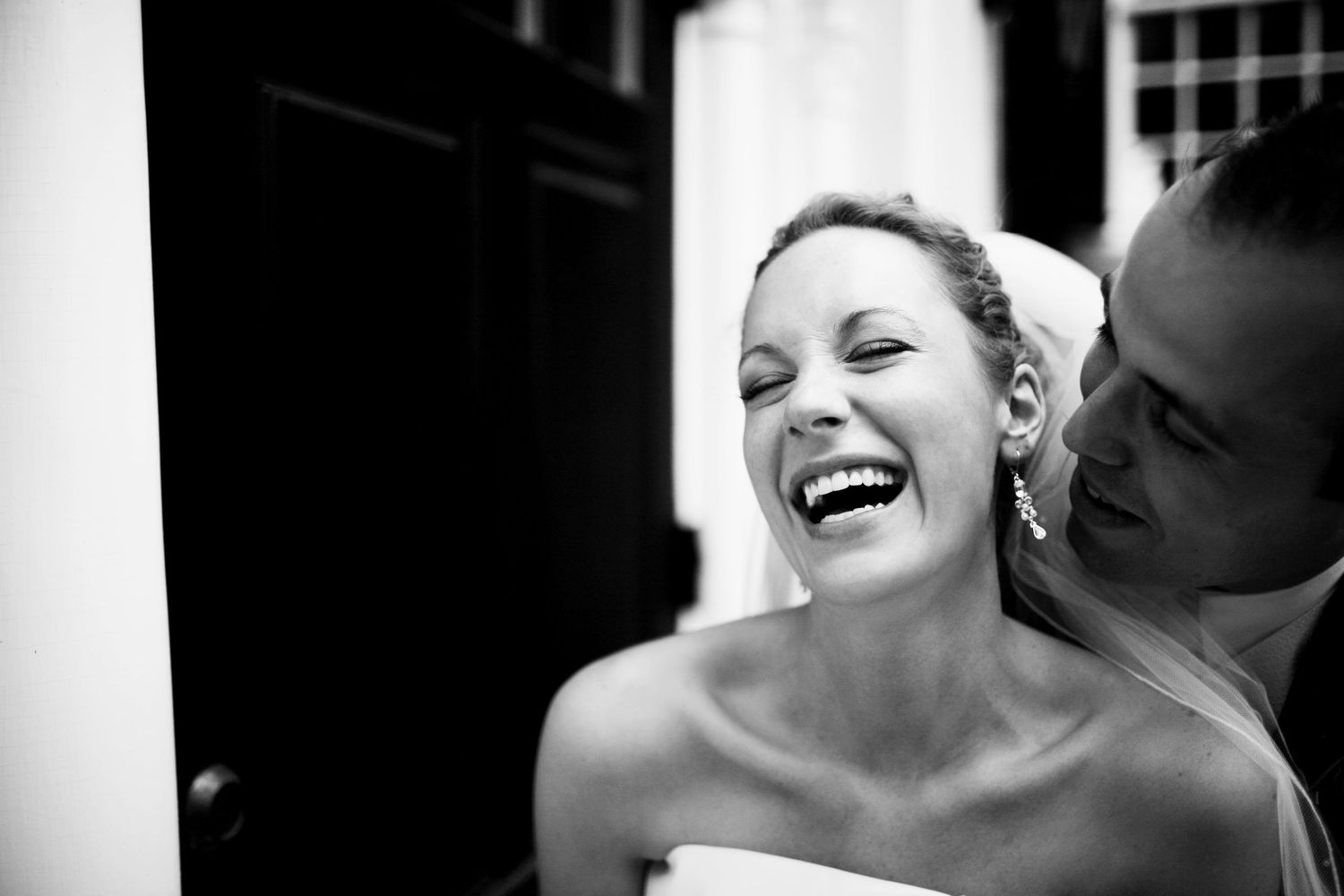 A black and white candid portrait captures a joyful moment showing genuine laughter and happiness.