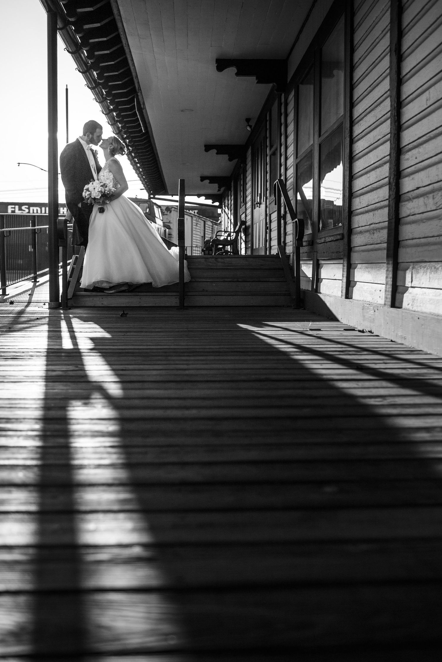 Black and white wedding photo on a covered porch with dramatic shadows.