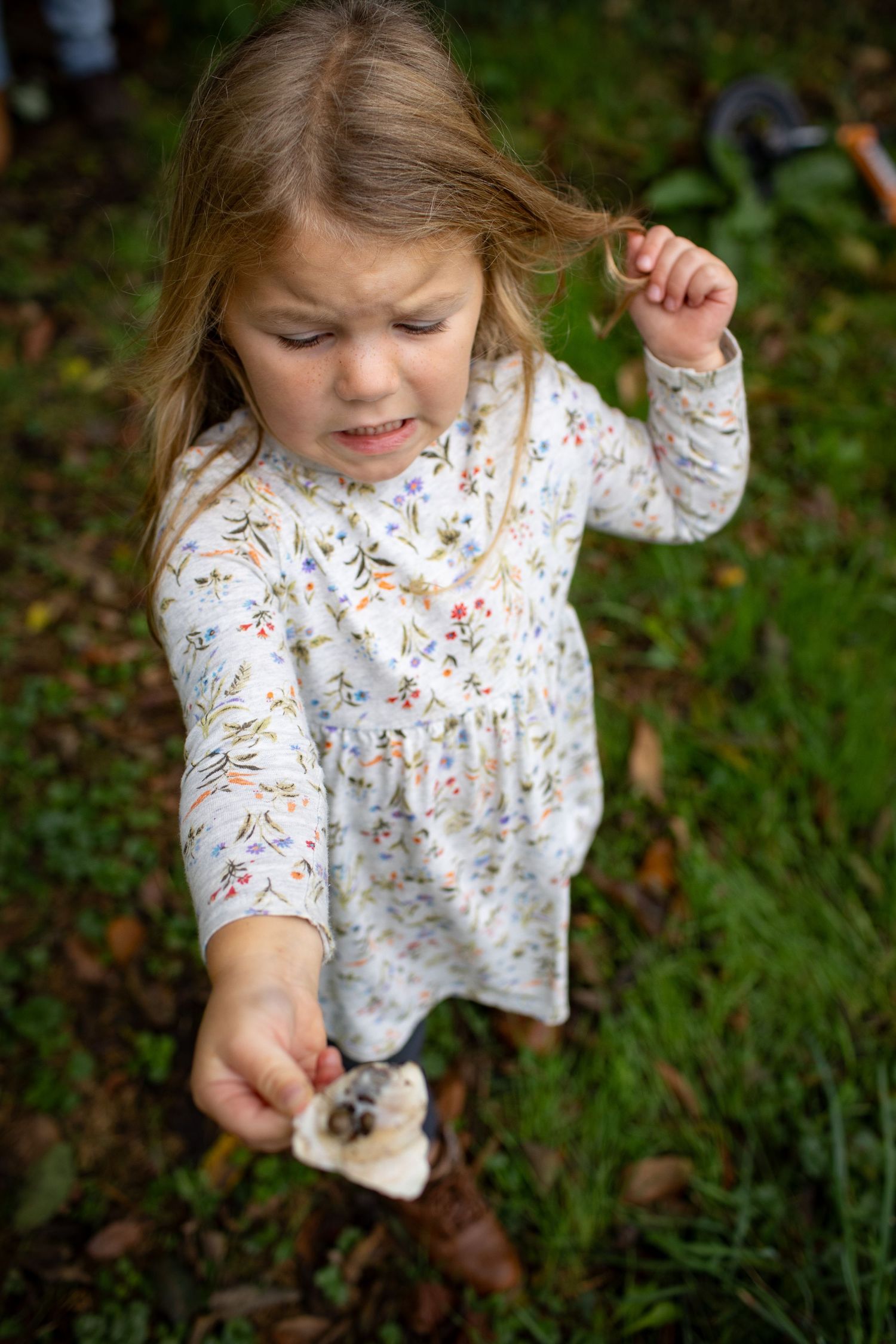 Close up shots of a child exploring and playing outdoors in a floral print dress.