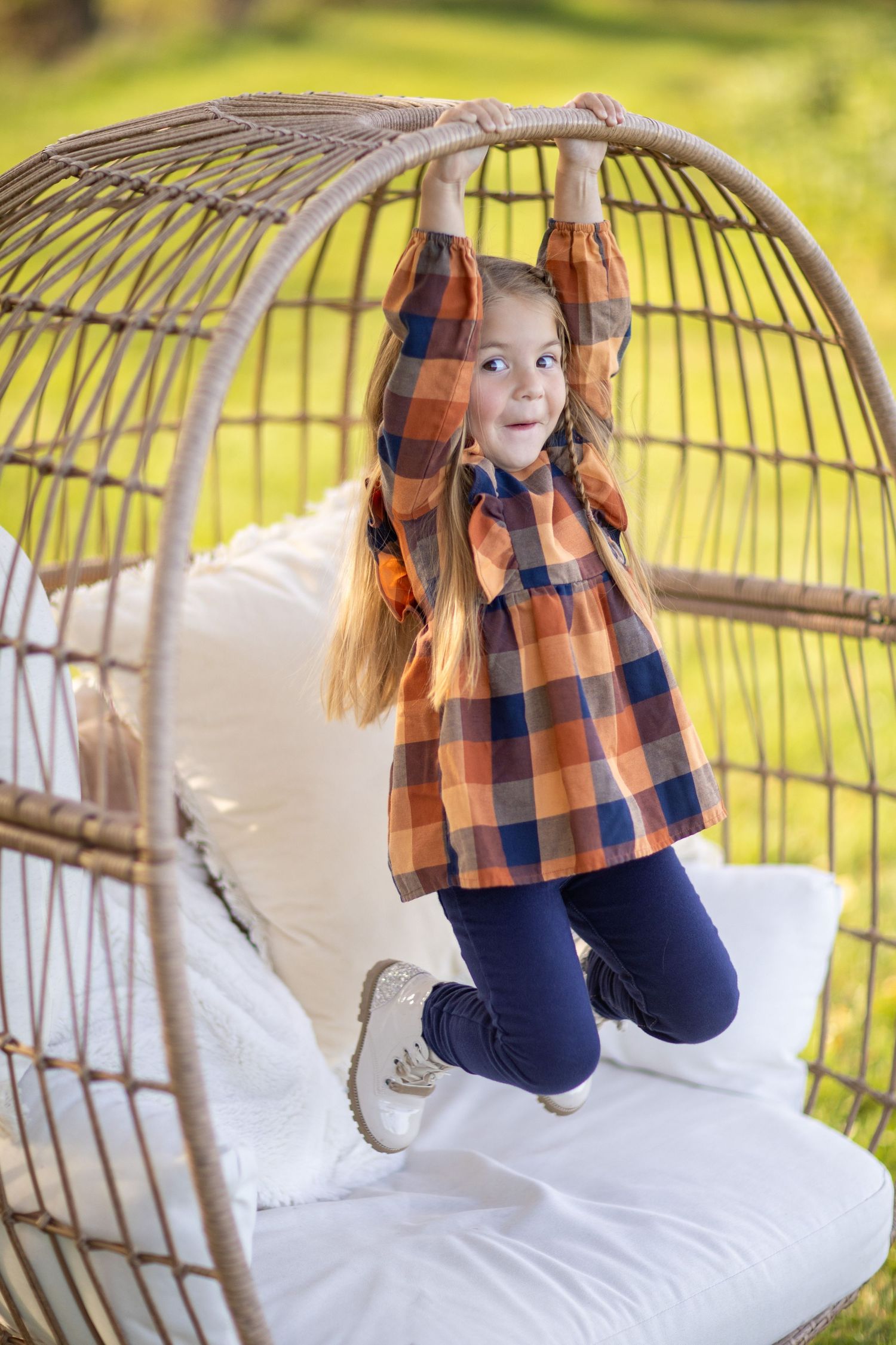 A sequence of playful moments on a hanging rattan egg chair with cushions against a sunny outdoor backdrop.