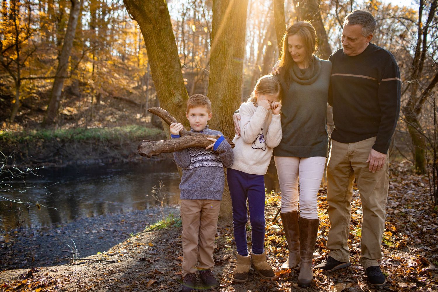 Family enjoys an autumn walk together along a sunlit wooded stream.