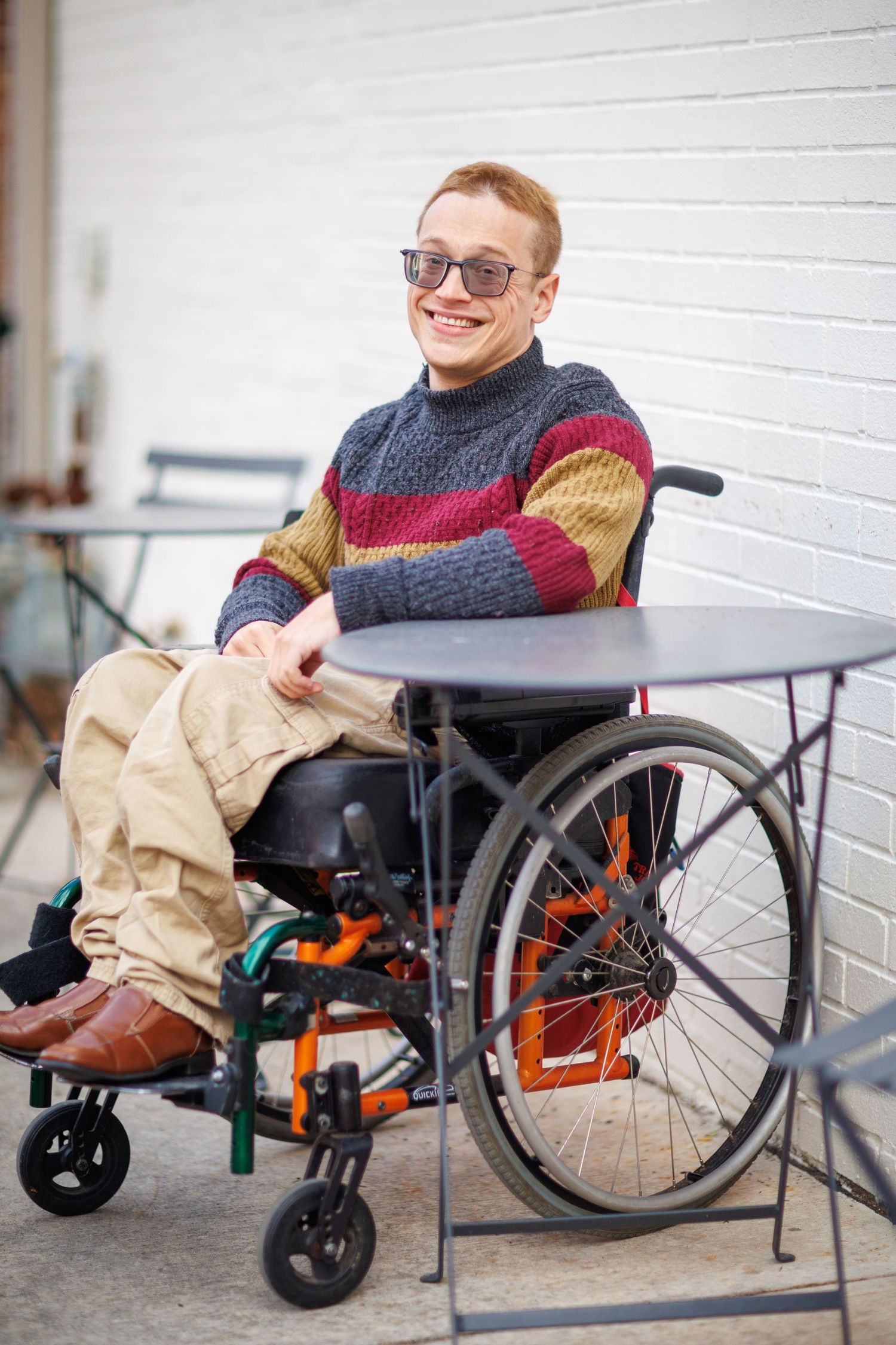 A series of photos showing someone in a wheelchair wearing a red sweater and khaki pants against a white wall.