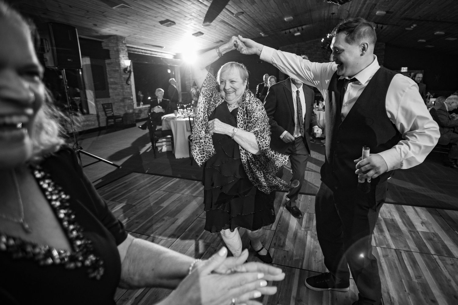 Guests dance joyfully on the dance floor during a lively wedding reception celebration.