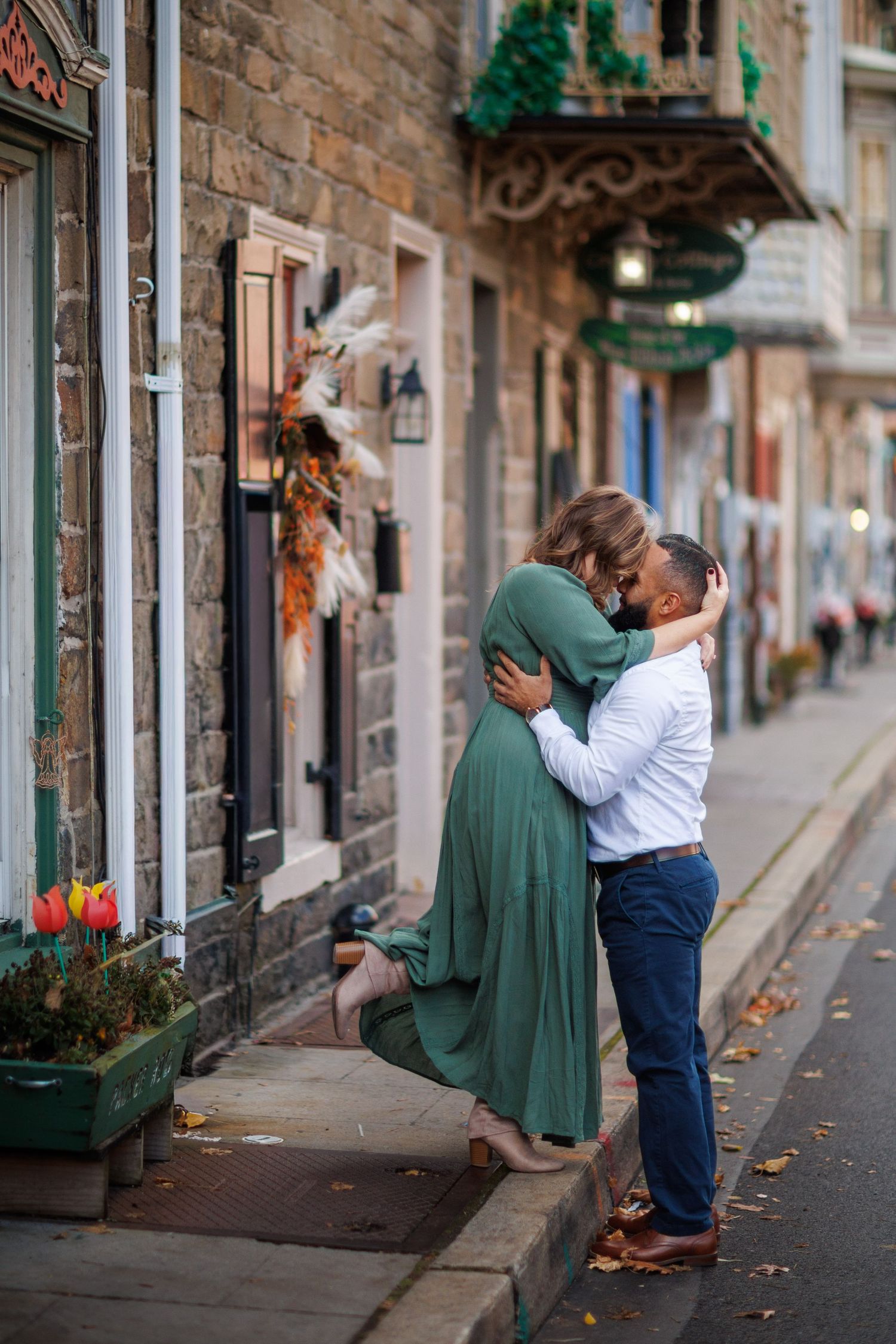 A romantic sequence of photos showing a couple embracing on a charming cobblestone street with stone buildings and greenery.