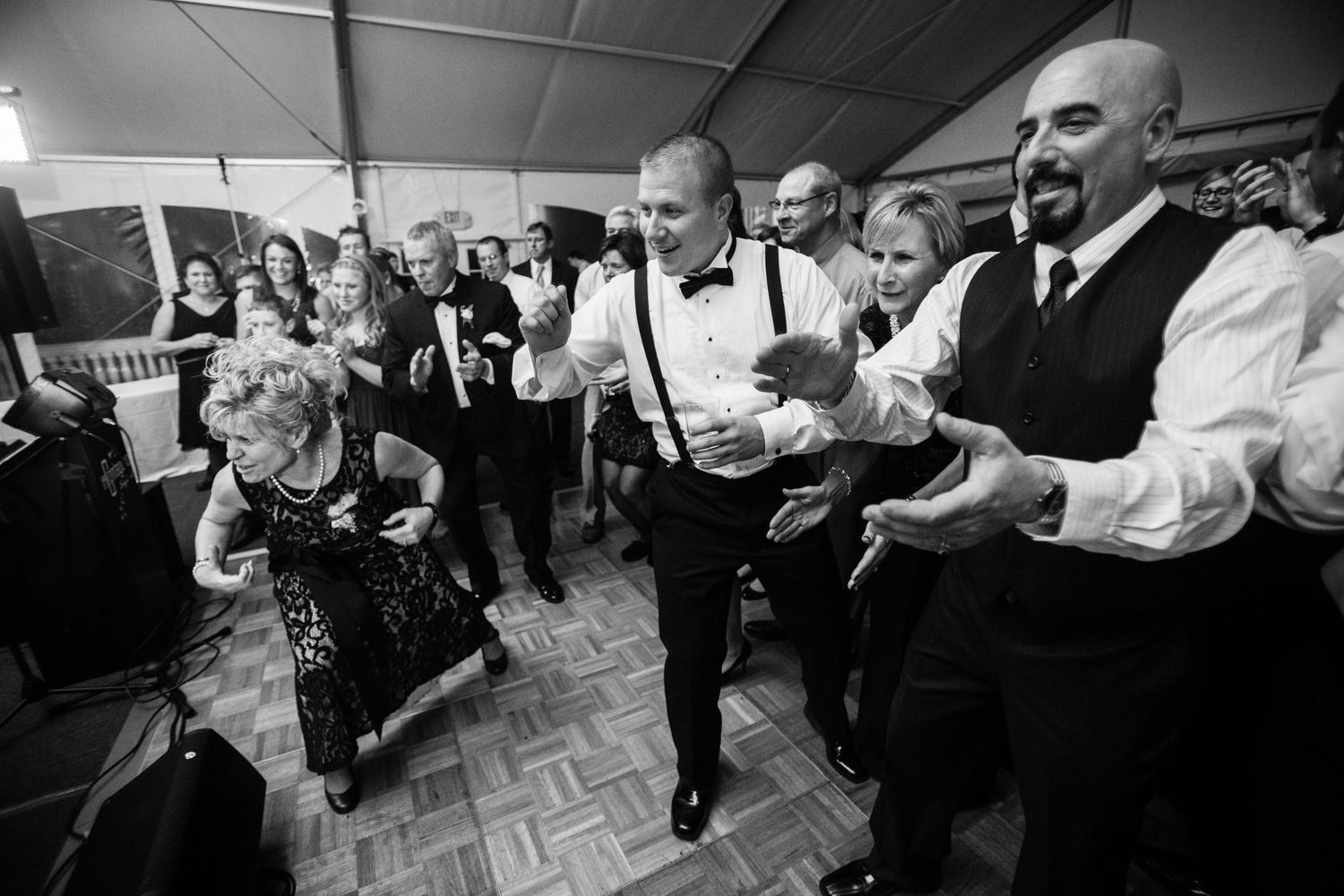 Party guests dance energetically on a checkered dance floor during a lively celebration.