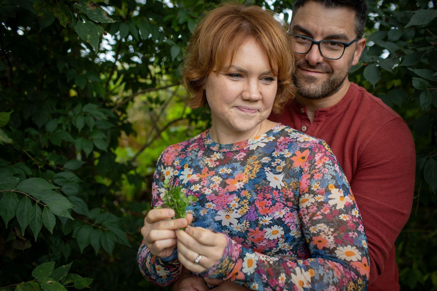 Couple sitting together outdoors wearing floral and burgundy clothing.
