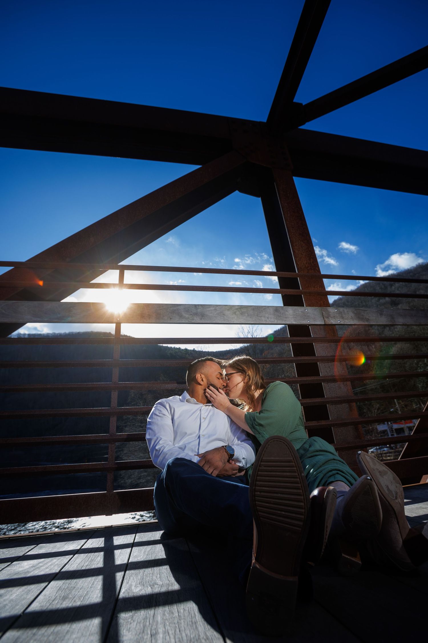 A sequence of silhouetted figures embracing against a bright blue sky with sunlight streaming through wooden beams.