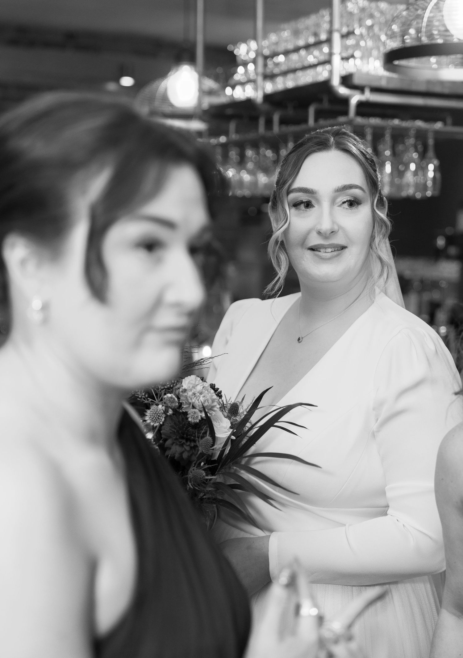 Black and white candid wedding photo showing guests and decor in an intimate indoor venue setting, New Craven Hall, Leeds.
