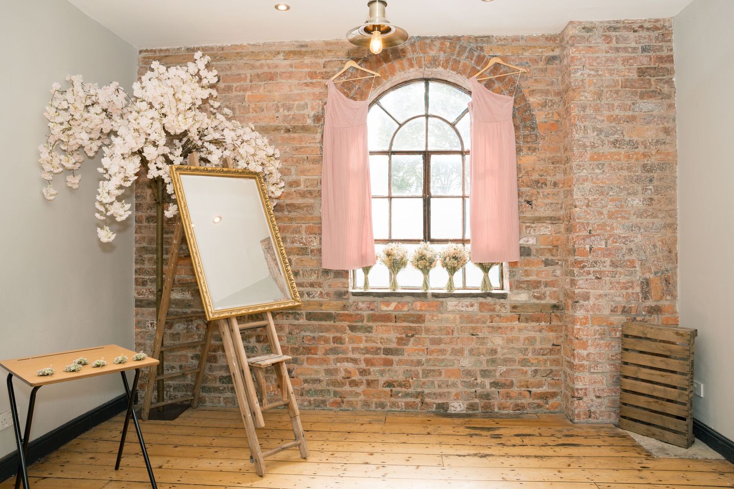 Rustic brick venue interior with arched windows and wooden floors for a wedding ceremony.