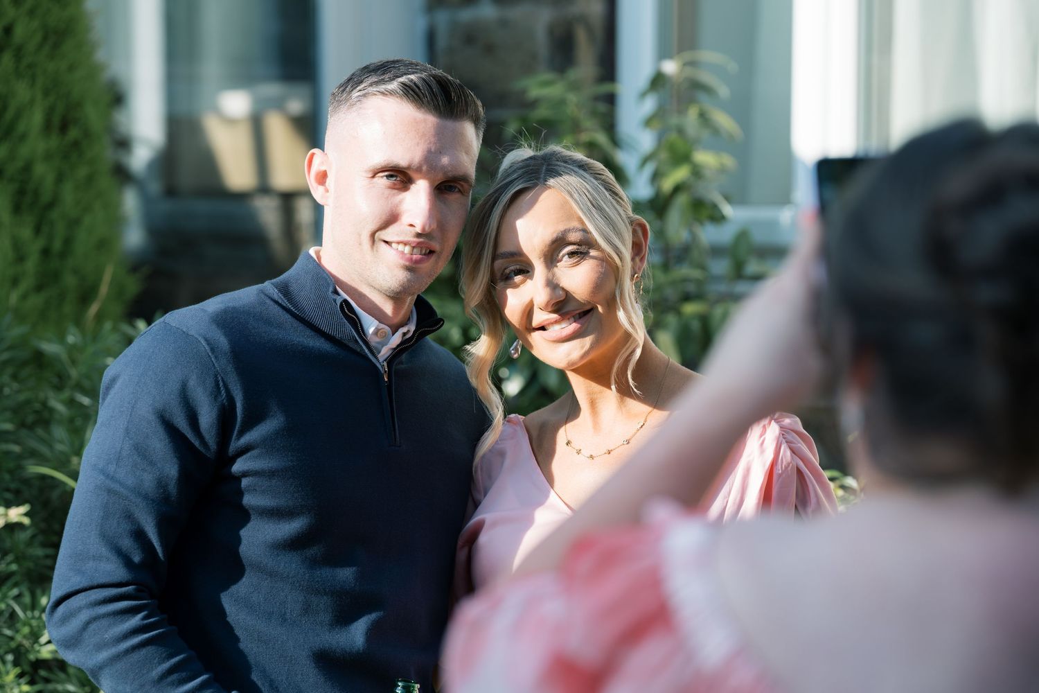 Elegant outdoor wedding scene with navy and white attire against white pillars.