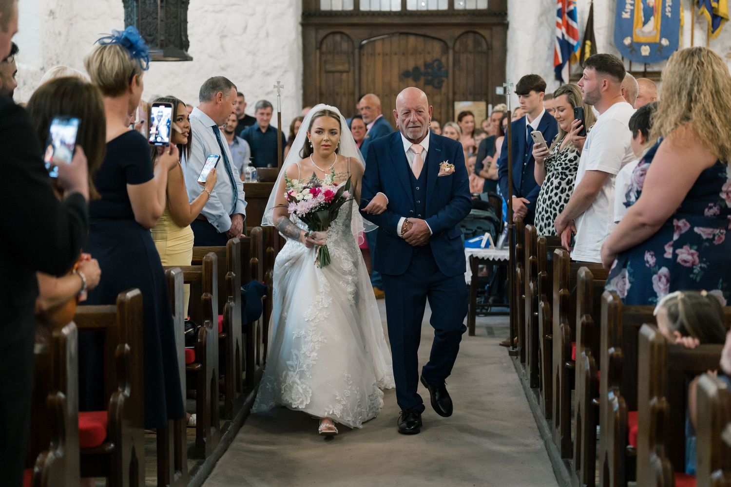 Wedding guests stand and watch as the bride walks down the church aisle during a traditional ceremony.