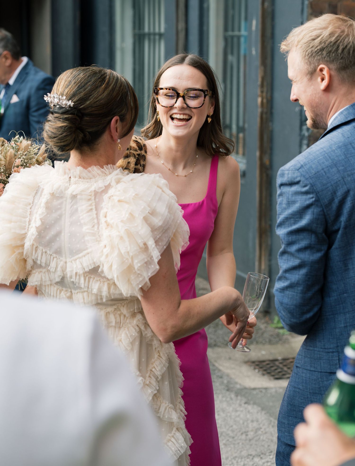 Wedding guests mingle and celebrate in formal attire with a bright pink dress standing out.
