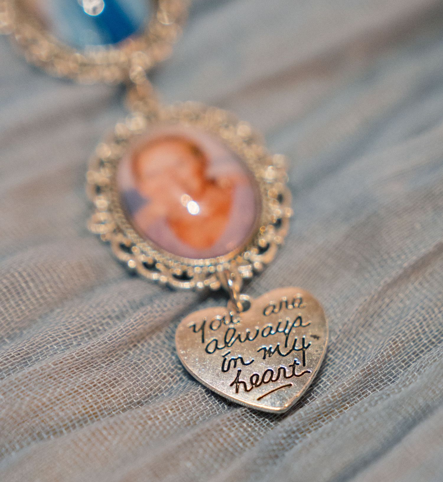 Two heart-shaped lockets with engraved text laid on textured fabric.