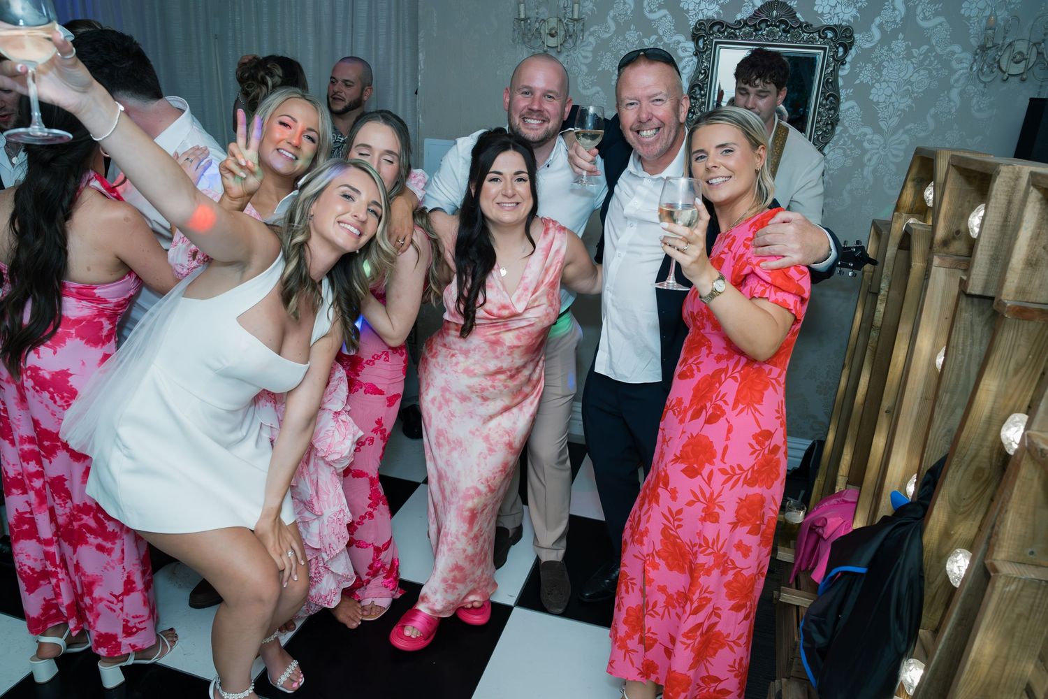 Wedding party dances together in formal attire at an indoor reception venue.