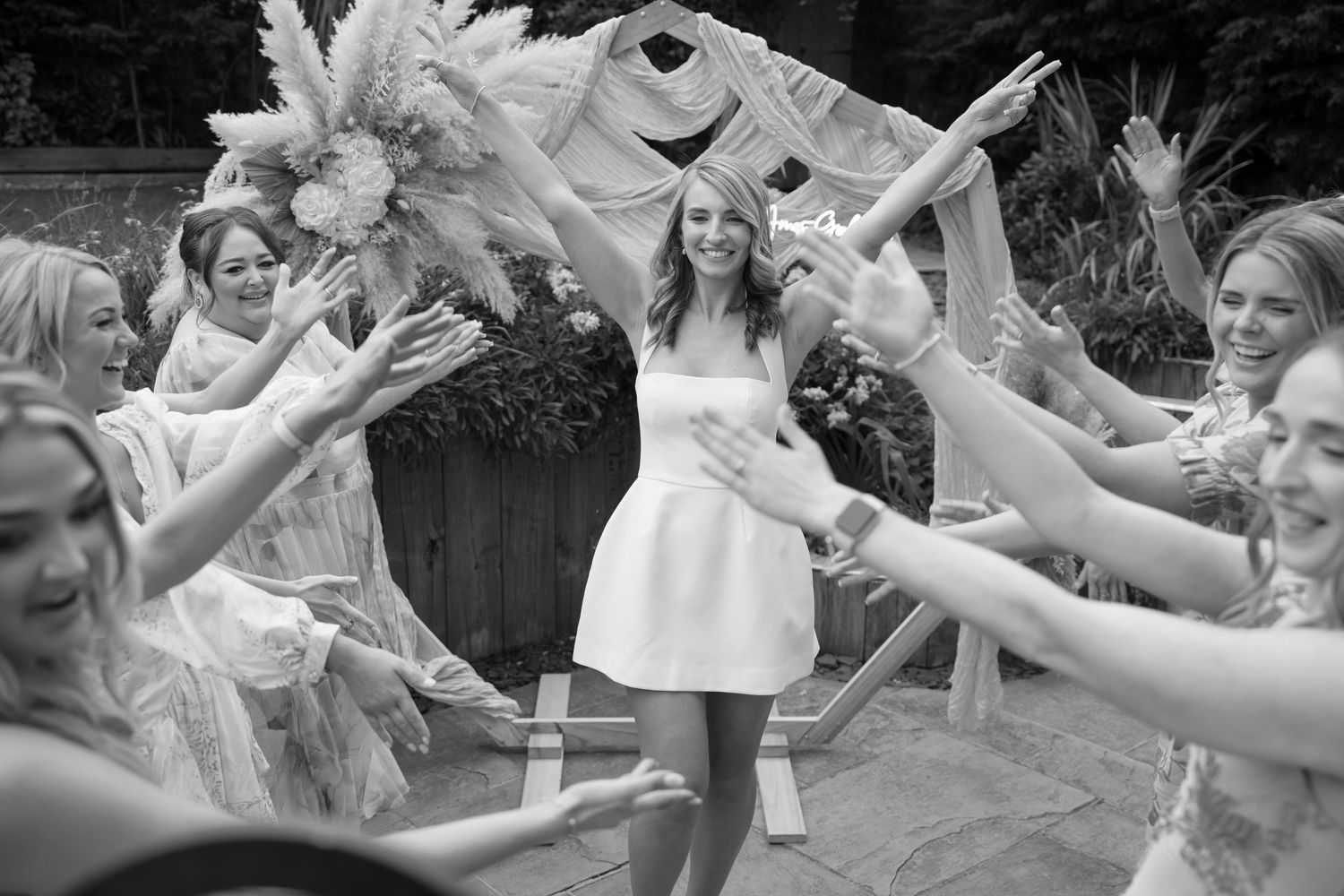 Wedding party members dancing and celebrating with joyful expressions during outdoor celebration.