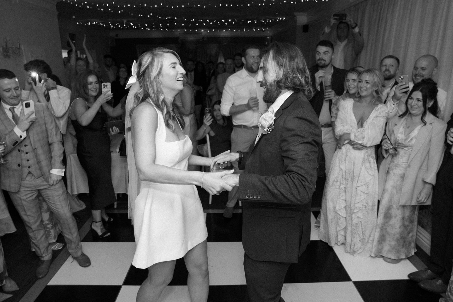 Wedding reception dance party with guests enjoying lively celebration in dimly lit venue.