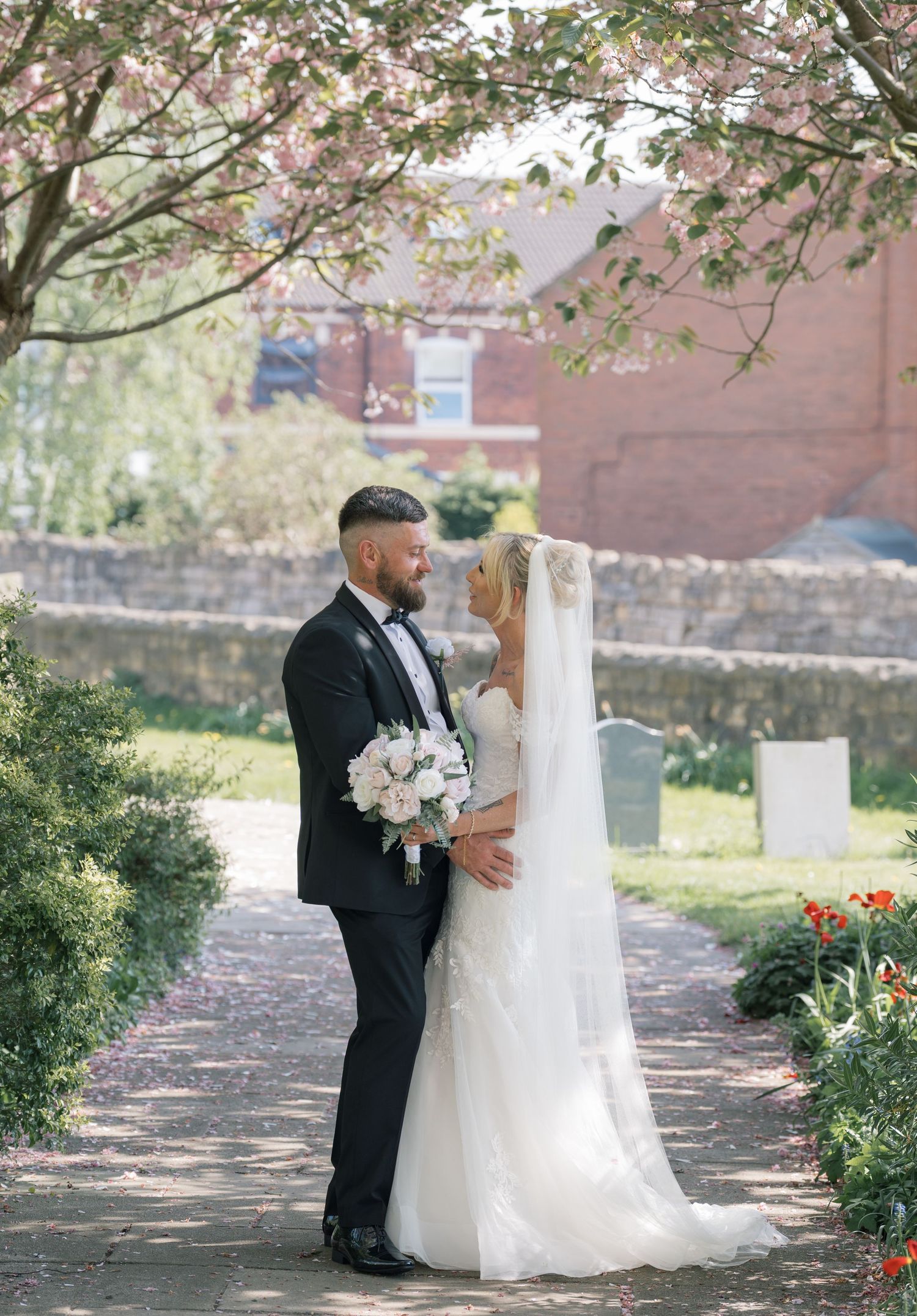 Bride and groom share romantic moment under blooming cherry blossom tree in a Leeds church.