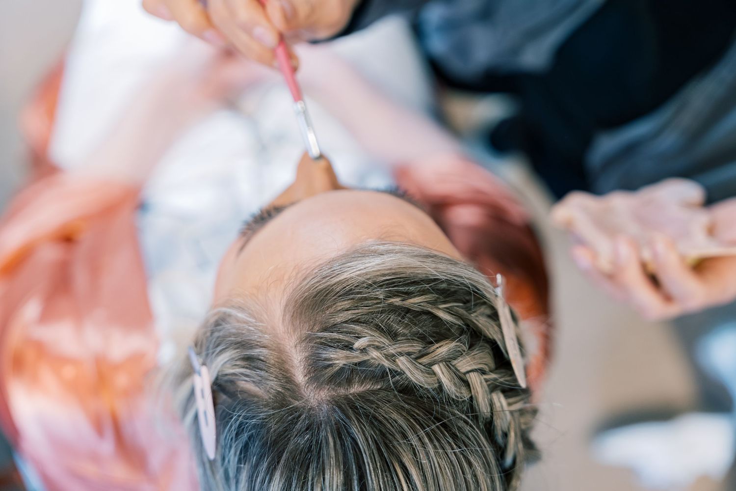 Close-up of an intricate braided hairstyle being styled for special occasion.