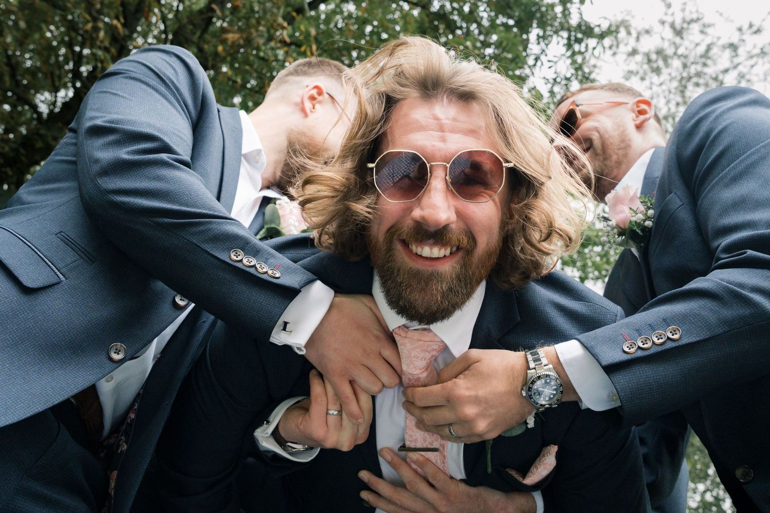 A joyful moment shared between wedding guests taking a fun group selfie outdoors.