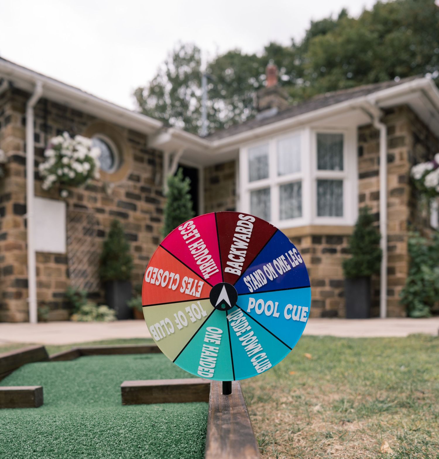 Colorful pool cue direction signs arranged in a circular pattern on grass.