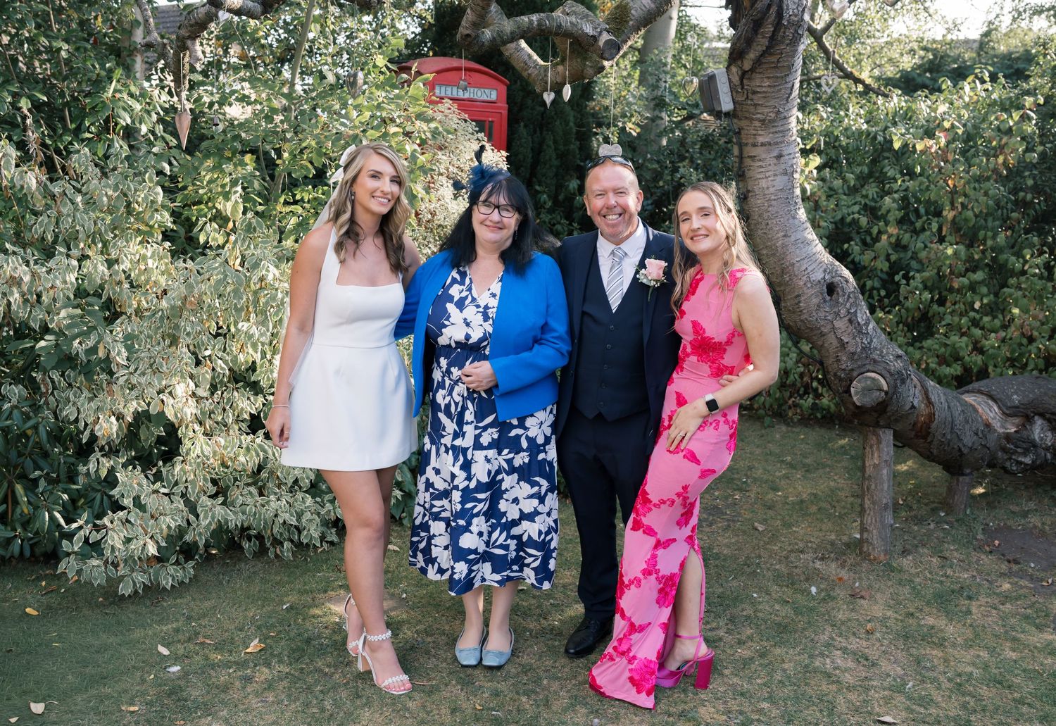 Garden wedding gathering with guests wearing bright summer dresses and formal attire.