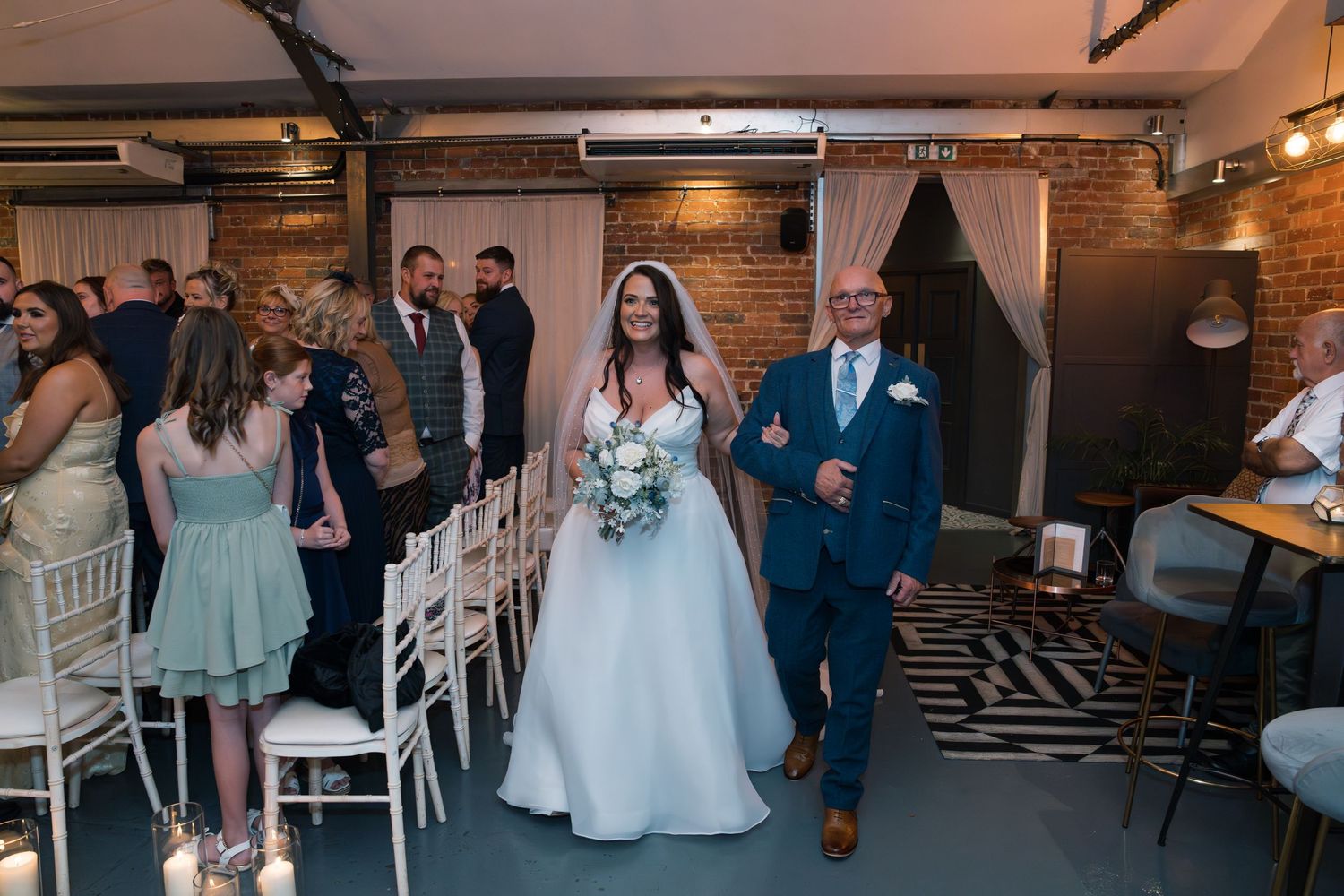 Wedding guests gathered in an industrial-style venue with exposed brick walls and modern furnishings.