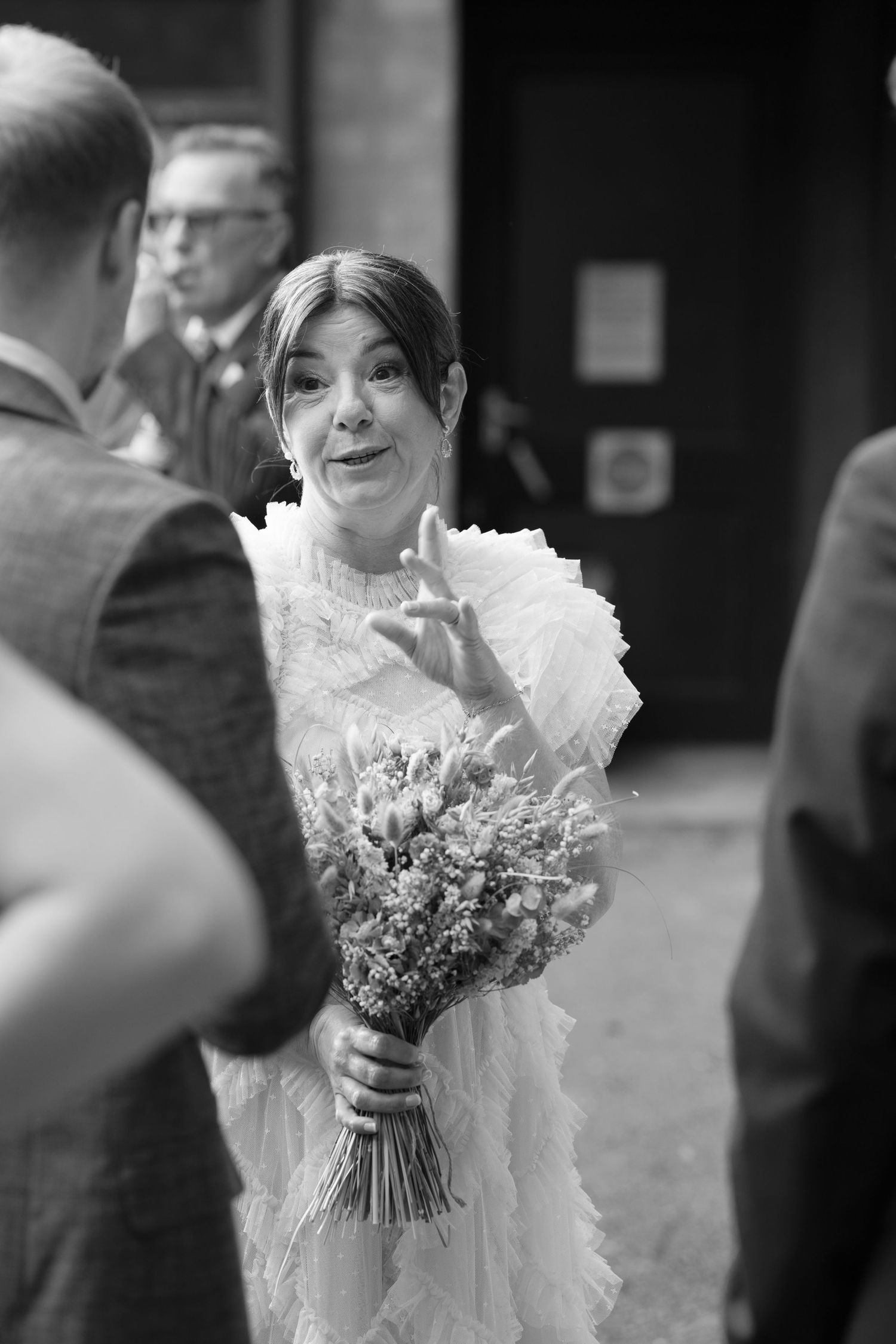 A bride in a ruffled white dress holds a beautiful wildflower bouquet.