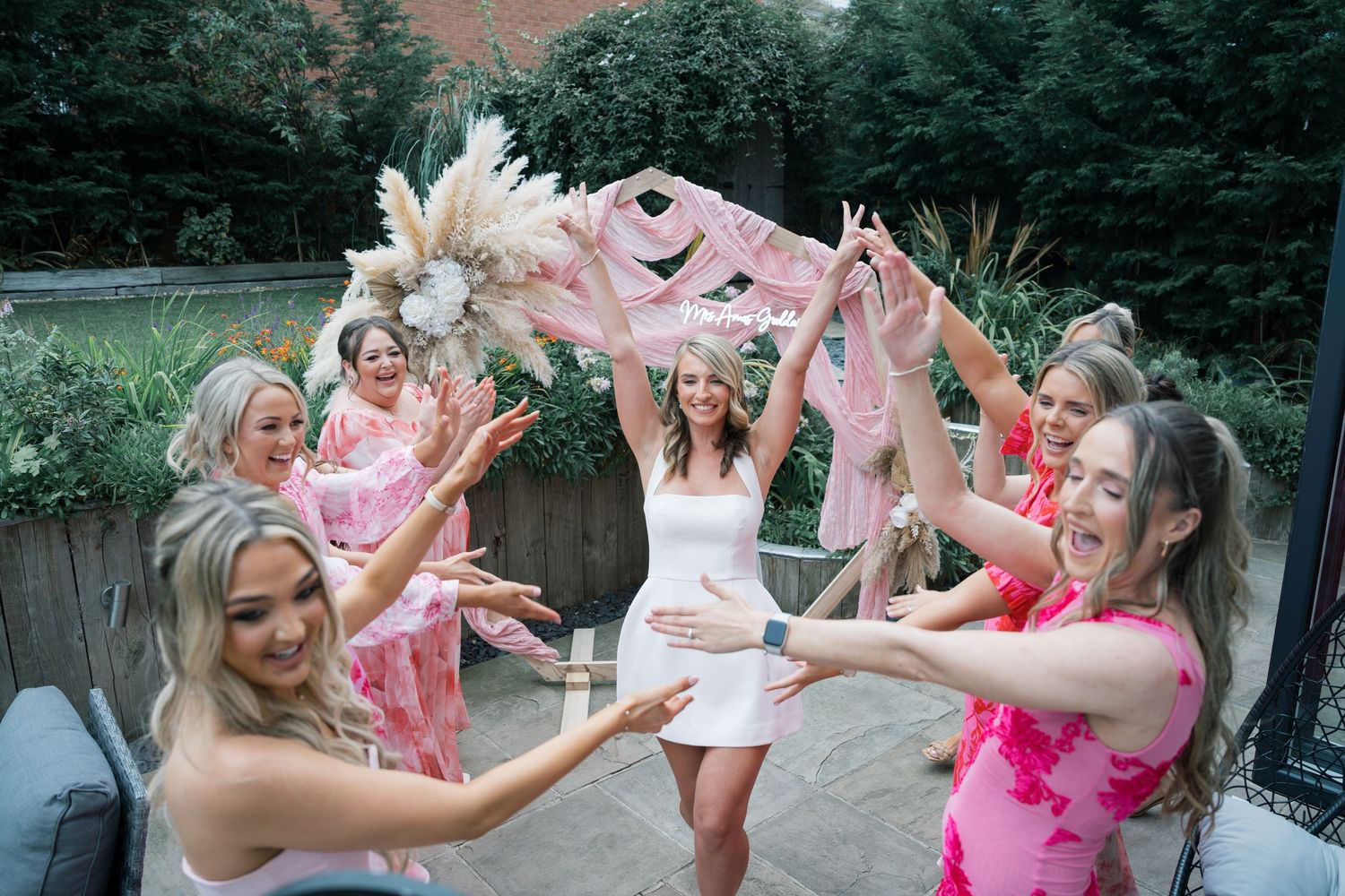 Group celebrating with pink powder paint throws at an outdoor party.
