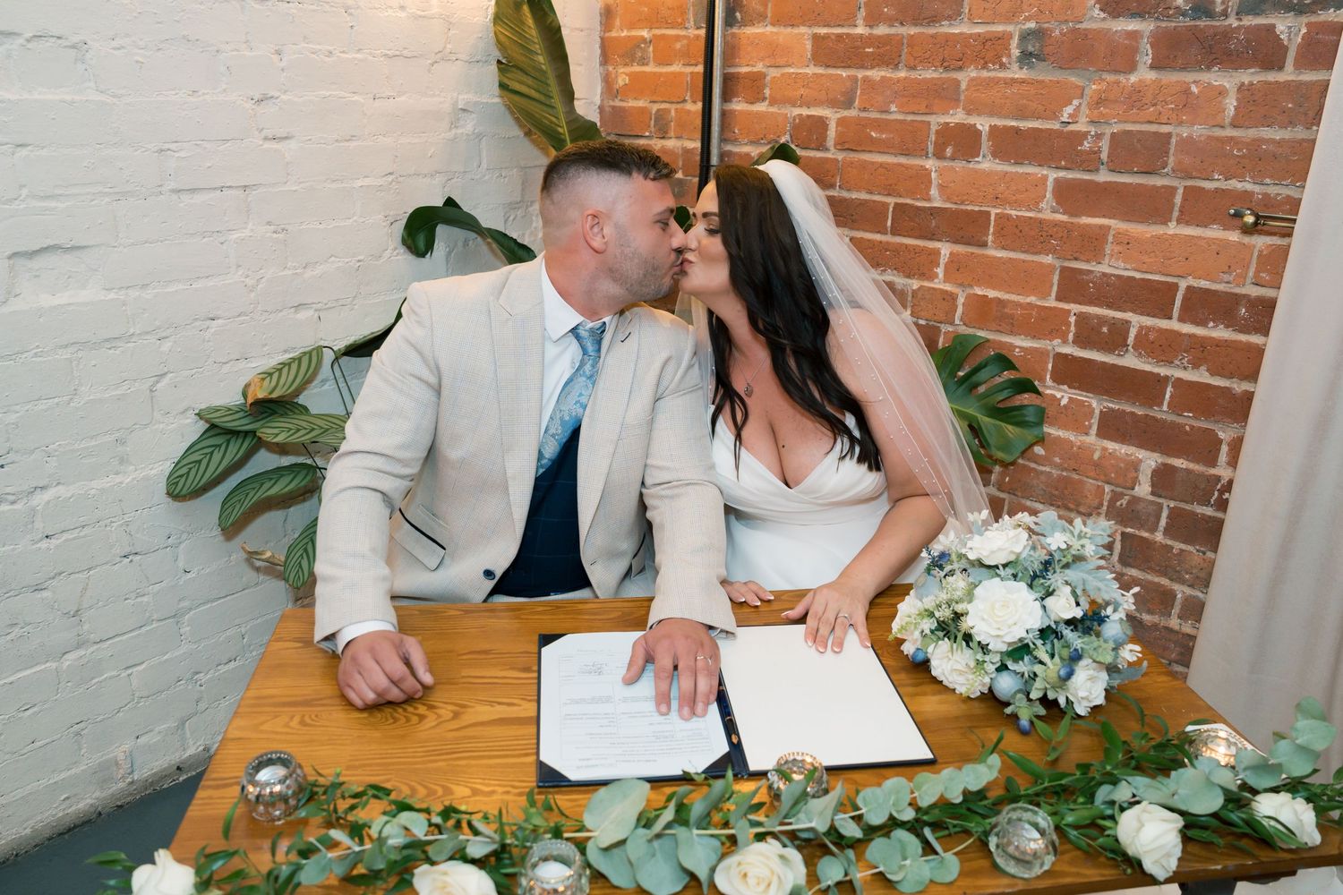 Wedding reception decor featuring exposed brick walls and elegant floral table arrangements.