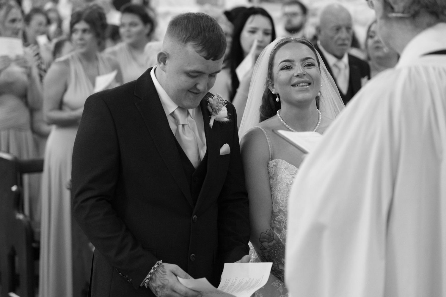 Dancing couples in formal wedding attire embrace on the dance floor during a black and white reception celebration.
