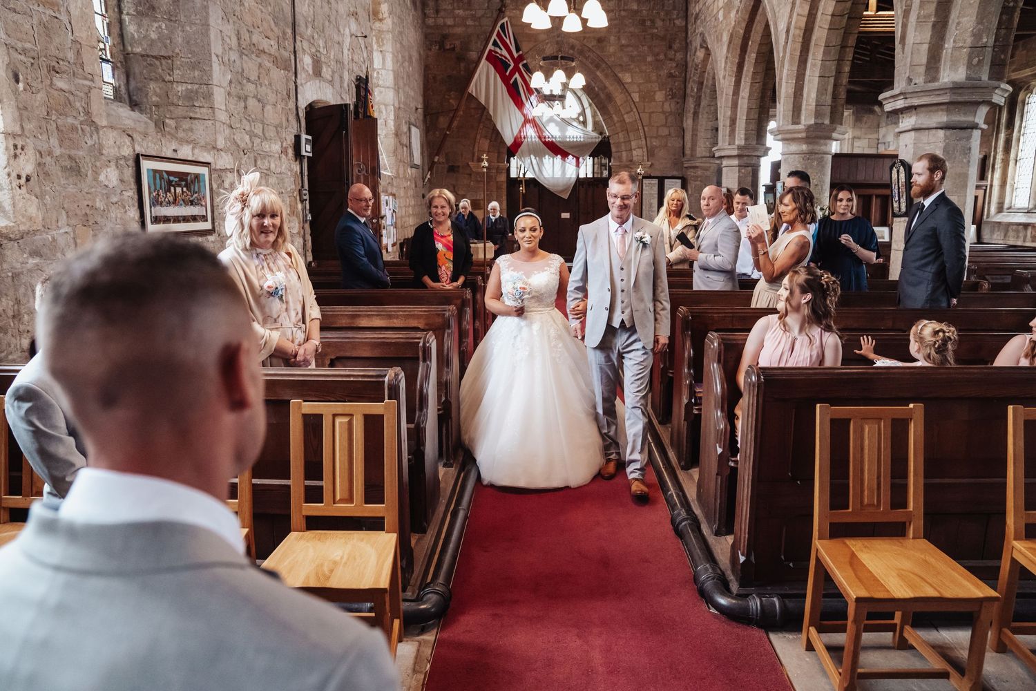 Traditional church wedding ceremony in historic stone building with red carpet aisle.