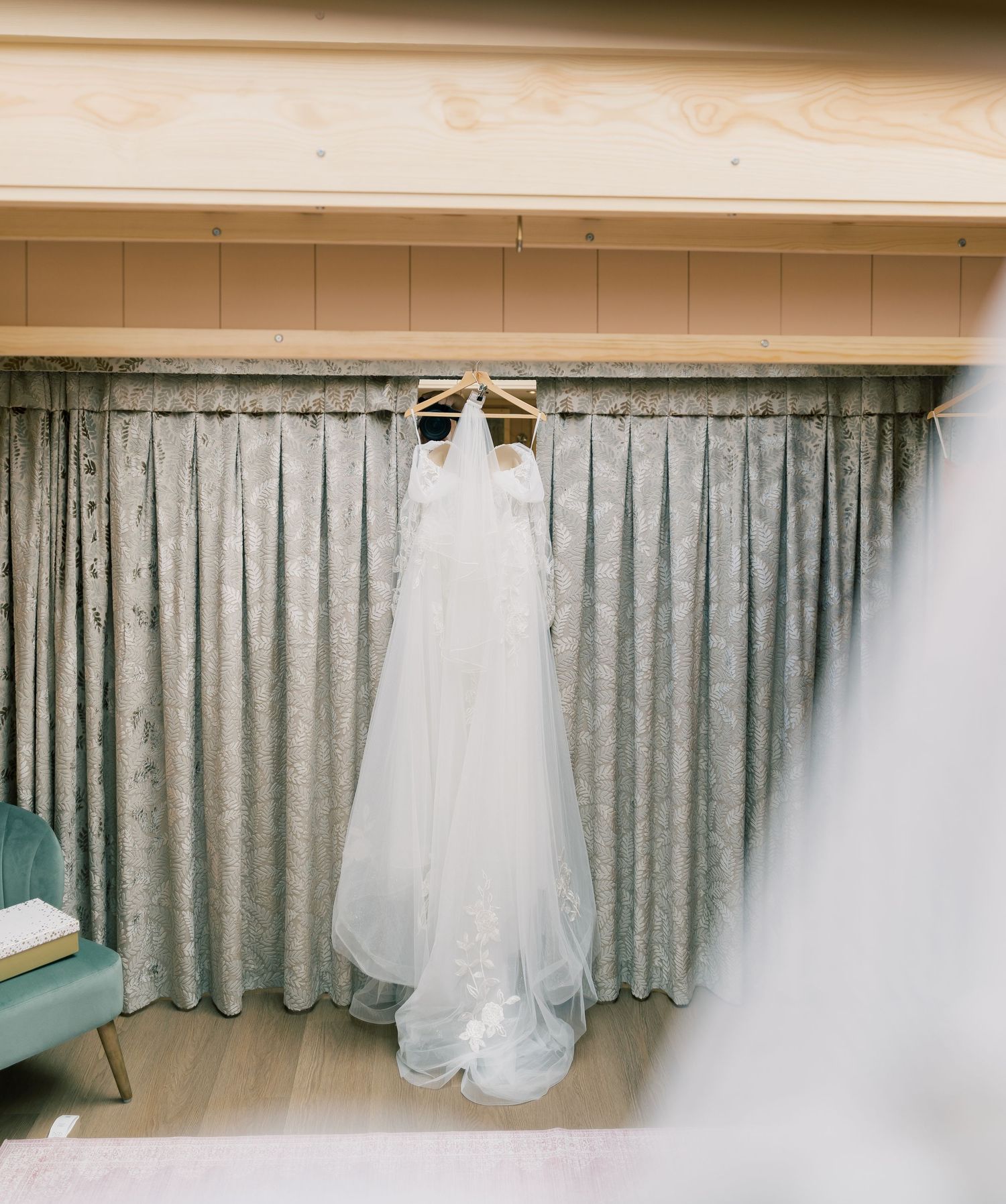 White wedding dress hanging on display against grey curtains in a dressing room.