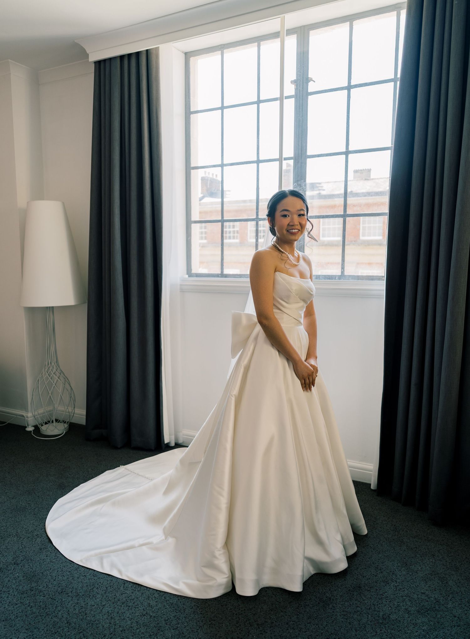 Wedding dress fitting room with natural light streaming through large window.