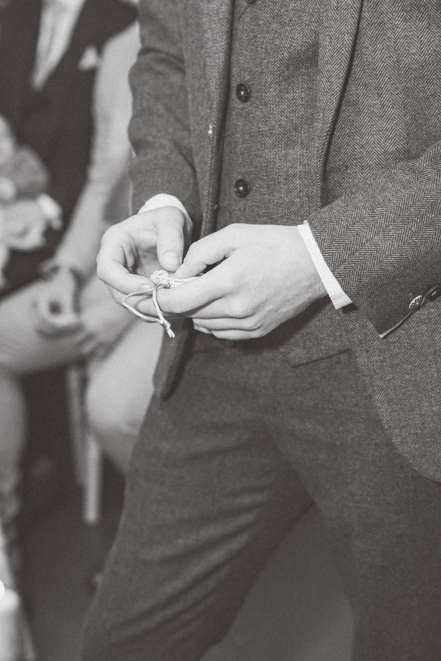Close-up monochrome image of hands adjusting formal attire details.