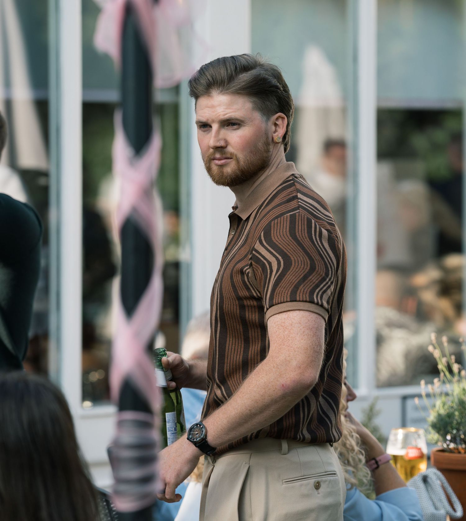 Guest in brown striped shirt mingling at outdoor event.