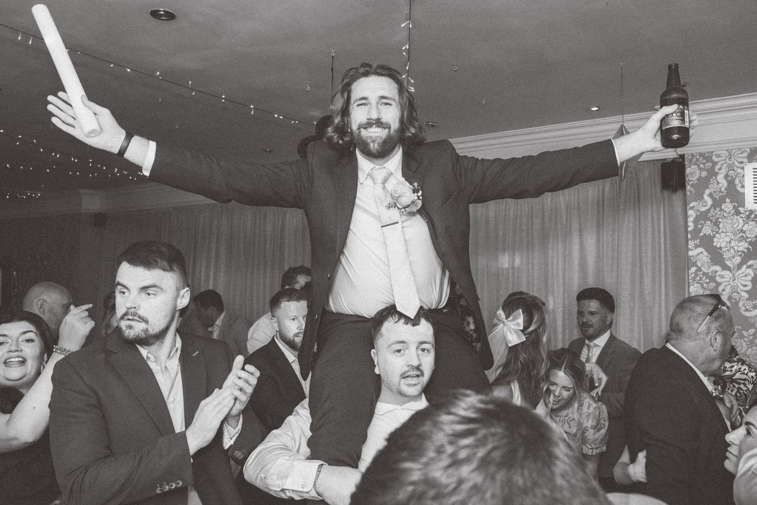 Wedding reception dance floor filled with guests celebrating and dancing under indoor lighting.