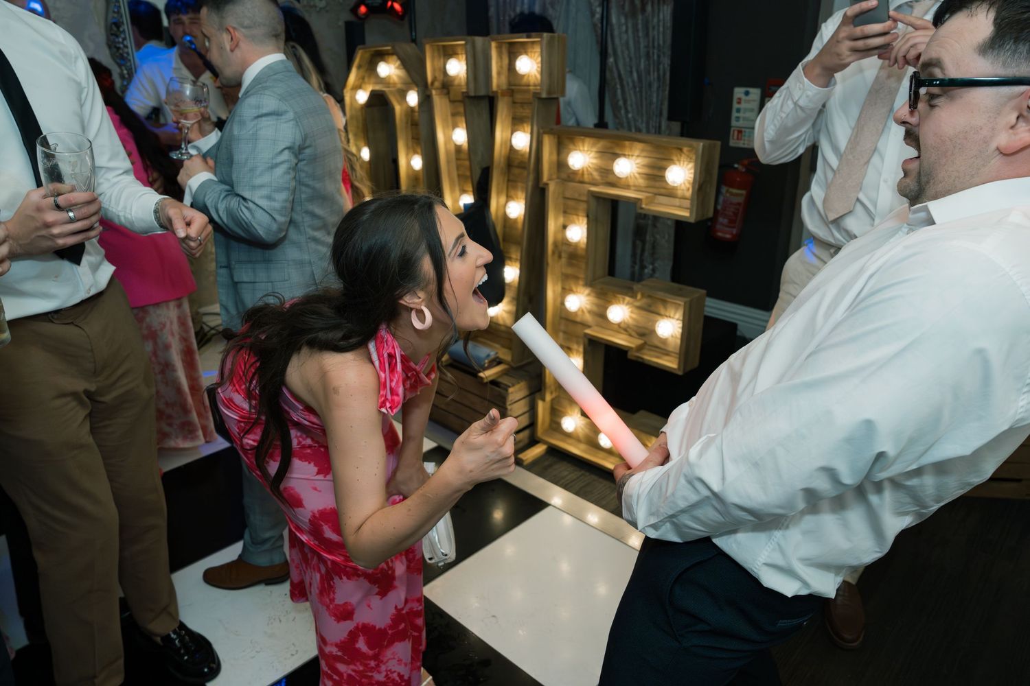 Wedding reception party scene with string lights and dancing guests.