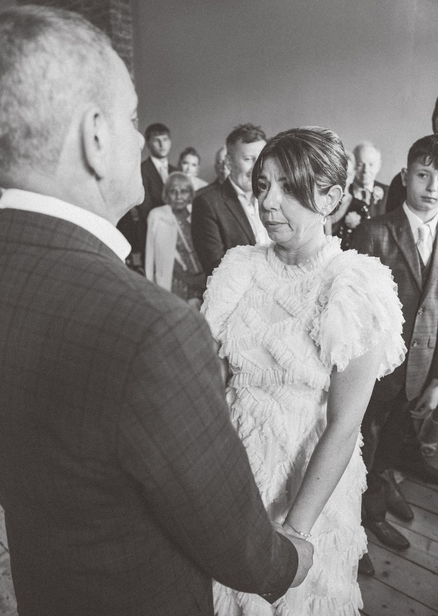 A wedding celebration showing guests and a bride in a textured white gown at an indoor venue.