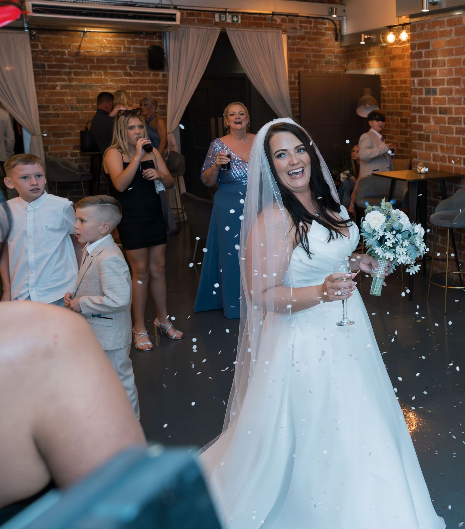 Wedding reception dance floor moments with string lights and brick wall backdrop.