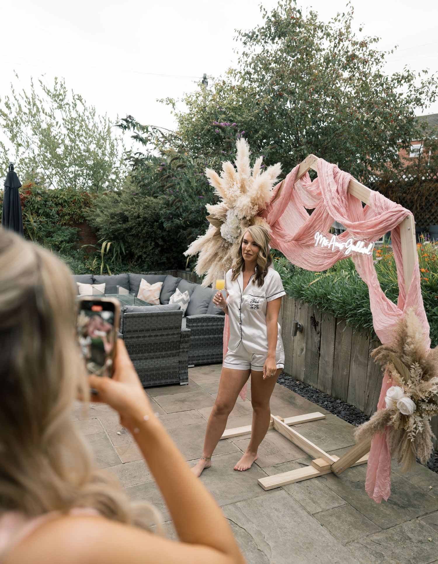 Person dancing with flowing pink fabric and pampas grass decorations in an outdoor setting.