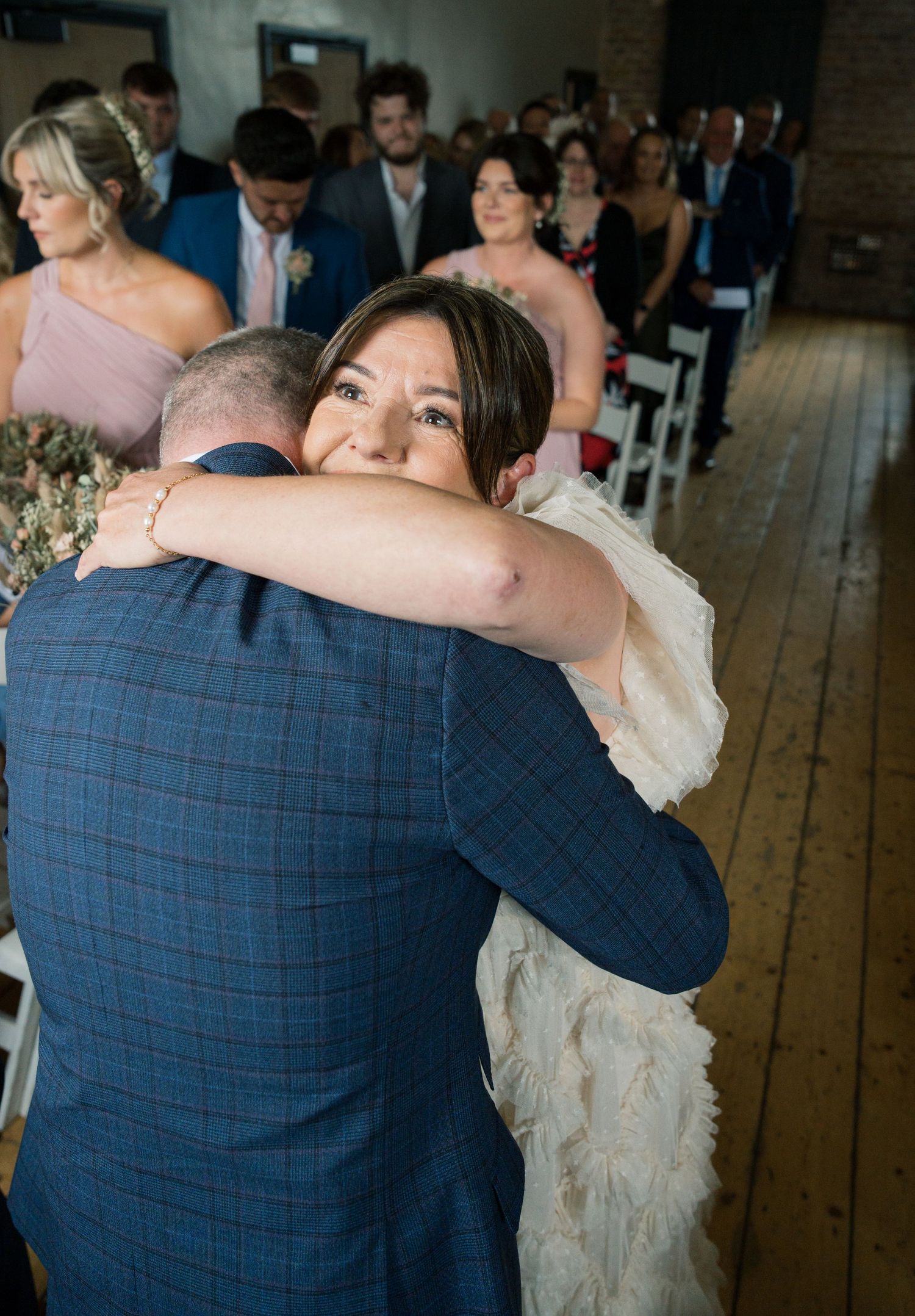 Wedding couple dancing in an intimate moment surrounded by guests in a rustic venue.
