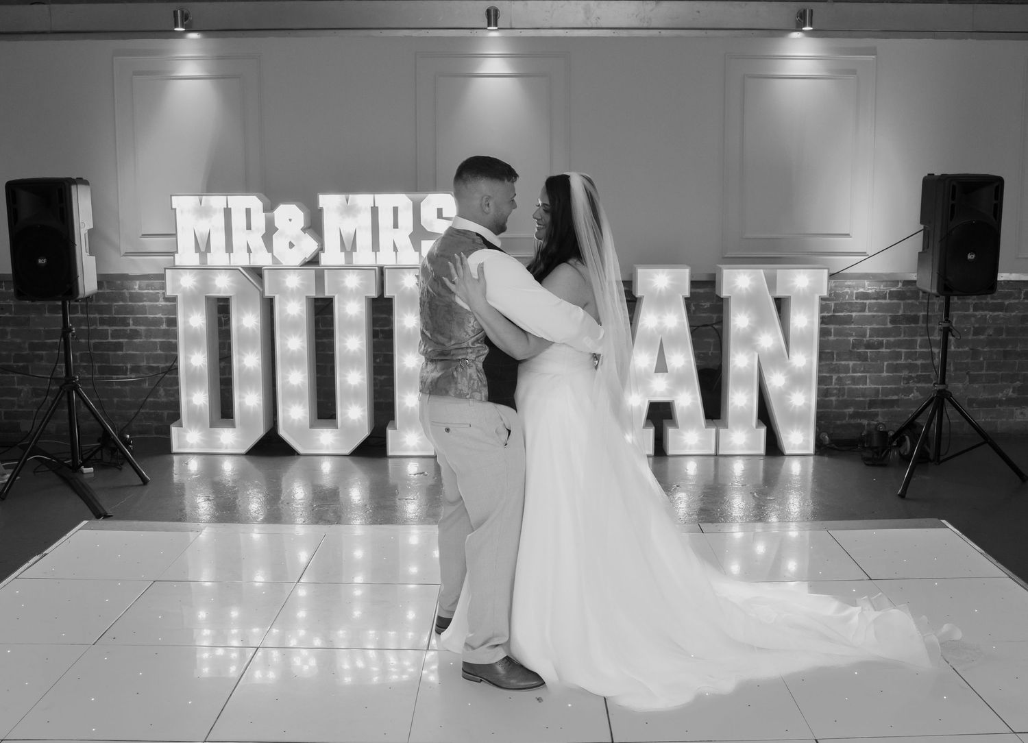 Illuminated wedding signage display in black and white at reception venue.