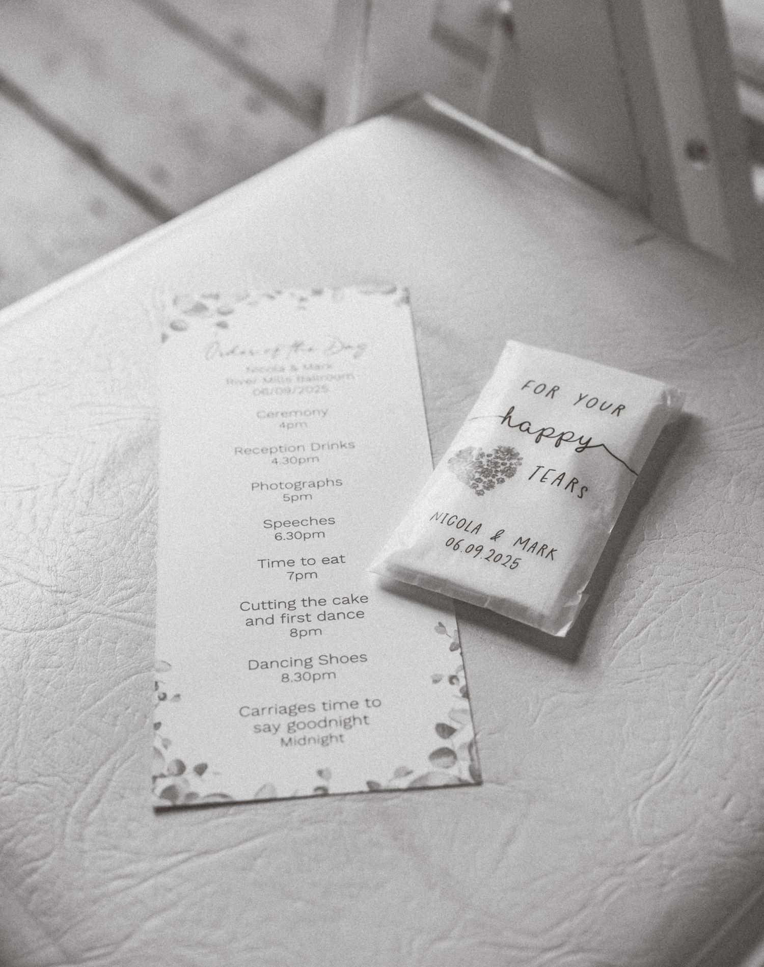 Wedding invitations and stationery laid out on a textured white surface in black and white.